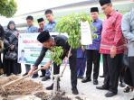 Kakanwil Kemenag Sumsel Syafitri Irwan menanam bibit pohon di lingkungan MAN 1 OKU, Minggu (8/2/2026), sebagai wujud komitmen gerakan Ekoteologi dalam menjaga kelestarian lingkungan.