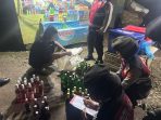 Personel Polda Sumatera Selatan menunjukkan ratusan botol minuman keras ilegal yang disita saat Operasi Pekat Musi 2026 di sejumlah warung di Palembang, Minggu (15/2/2026) malam.
