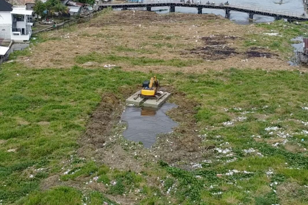 Alat berat milik PUPR OKI mengeruk tumpukan eceng gondok yang menutupi aliran sungai di Jembatan Desa Belanti, Kecamatan Sirah Pulau Padang, guna mencegah risiko banjir dan melancarkan kembali arus air.